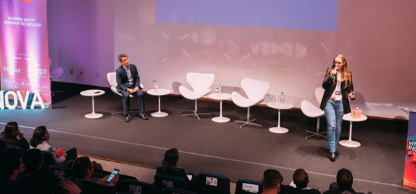 Palestrante se apresenta em um palco diante da plateia